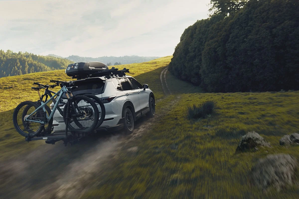 White Mitsubishi Outlander Trail with bikes and roof rack